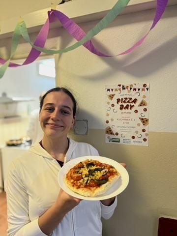 Študentka s hotovou pizzou a plagátom Pizza Day